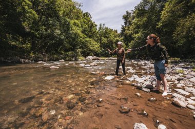 Anne ve kızı nehir kenarındaki suya taş atma oyunu oynuyorlar..