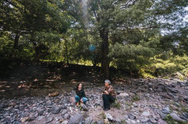 Anne ve kızı bir süre dinlenip nehir kenarında konuşuyorlar..