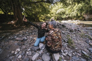 Anne ve kızı yeni yapılmış apachetalarının yanında fotoğraf çekiyorlar. Nehrin kenarında, gülümsüyorlar ve anın tadını çıkarıyorlar..