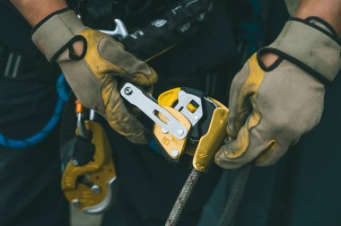 Firefighter and rescuer putting on harness, carabiners, and rappelling equipment to practice rappelling down a multi-story building.