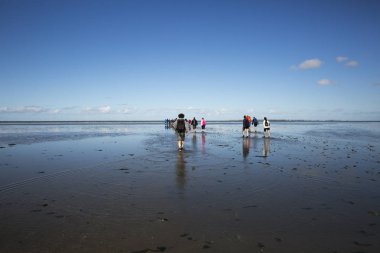 Düşük tide su ve bir grup insan Waddenzee, Friesland, Hollanda trekking, bulutlarda yansıması ile deniz manzara