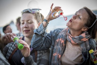 Traena, Norveç - 12 Temmuz 2014: İzlandalı şarkıcı Mugison'un Traenafestival'deki konseri sırasında baloncuk yaparken eğlenen genç kadınlar, traena adasında düzenlenen müzik festivali