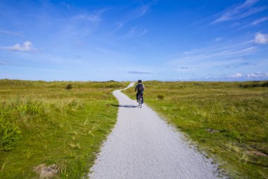 Frizian Island Amsland, Hollanda kumul manzara ile bir bisiklet yolu üzerinde bisiklet etekli insanlar