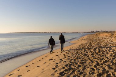 romantik kış gün batımı ile sahilde yürüyen insanlar