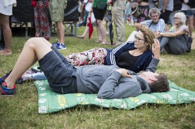 Amsterdam, Hollanda - 5 Temmuz 2015: Amsterdam Roots Open Air, Park Frankendael'de 05/07/2015 tarihinde düzenlenen kültür festivali sırasında çimenlerin arasında yatan genç çift