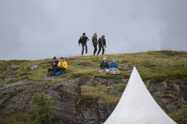 Traena, Norveç - 6 Temmuz 2017: Traenafestival'de bir tepenin tepesinde dans eden insanlar, küçük Traena adasında müzik festivali gerçekleşiyor