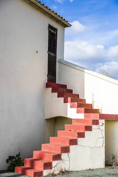 red stairs outside a house, with blue sky with white clouds background
