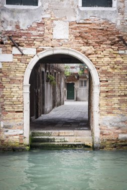 İtalya 'da Venedik' te bir kanalın yanındaki turuncu tuğla binanın küçük arka kapısı.
