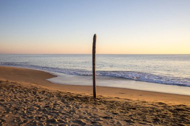 altın kum ve sessiz deniz ile gün batımında bir plajda görünümü