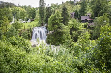 Ağaçlar ve bir şelale ile yeşil bir manzara ahşap evler ile bir nehir kanyon u Rastoke Hırvat köyü, Hırvatistan