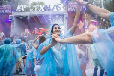 Amsterdam, Hollanda - 29 Temmuz 2017: Westerpark'taki Milkshake Festivali'nde yağmur ponçolarıyla yağmur altında dans eden insanlar