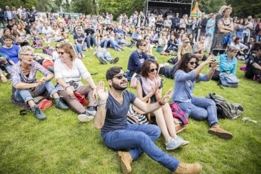 Amsterdam, Hollanda - 3 Temmuz 2016: Roots Open Air festivali sırasında çimlerin üzerinde oturan ve tezahürat eden ziyaretçiler