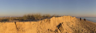 romantik kış gün batımı ile sahilde yürüyen insanlar