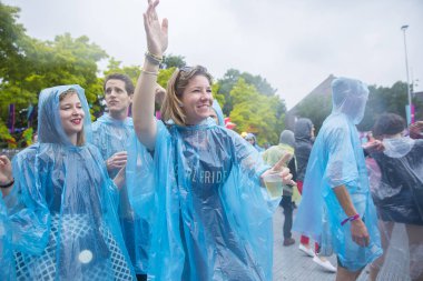 Amsterdam, Hollanda - 29 Temmuz 2017: Westerpark'taki Milkshake Festivali'nde yağmur ponçolarıyla yağmur altında dans eden insanlar