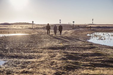 Doğal rezerv Casse de la Belle Henriette, l'Aiguillon sur Mer, Vendee, Fransa lagün tarafından gün batımında yürüyen insanların arkadan aydınlatmalı siluetler