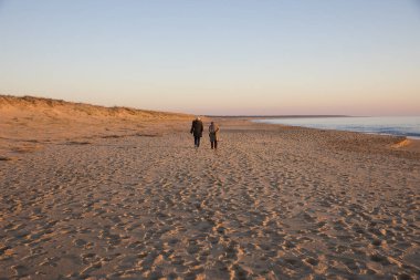 romantik kış gün batımı ile sahilde yürüyen insanlar