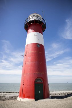 Mavi gökyüzü arka plan üzerinde kırmızı ve beyaz deniz feneri, Westkapelle, Hollanda