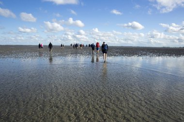 Düşük tide su ve bir grup insan Waddenzee, Friesland, Hollanda trekking, bulutlarda yansıması ile deniz manzara