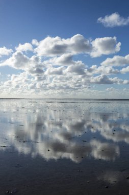 Deniz manzarası bulutların alçak gelgit sularındaki yansıması, Waddenzee, Friesland, Hollanda