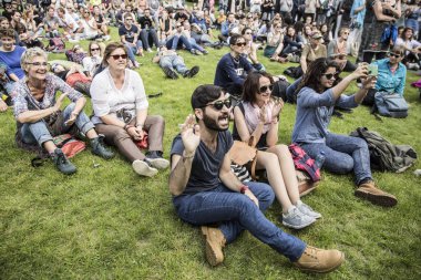 Amsterdam, Hollanda - 3 Temmuz 2016: Roots Open Air festivali sırasında çimlerin üzerinde oturan ve tezahürat eden ziyaretçiler