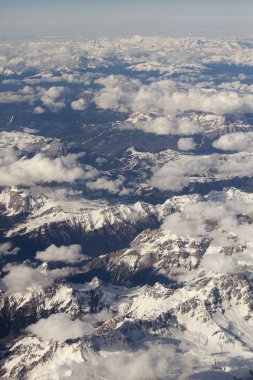 Bulutlardaki Alp dağlarının karlı zirvelerinin havadan görünüşü