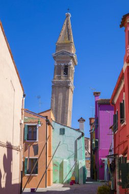Burano, İtalya - 22 Mart 2018: San Martino Kilisesi'nin canlı renkleri ve kulesiyle renkli cepheler ve İtalya'nın Venedik adasındaki ünlü balıkçı lar köyünde ki eğimli kampçısı