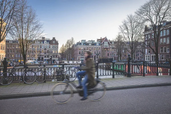 在阿姆斯特丹的街头生活场景 一座桥上停着自行车 一个骑自行车的人在桥上和典型的荷兰运河房屋上骑自行车 荷兰阿姆斯特丹 — 图库照片