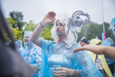 Amsterdam, Hollanda - 29 Temmuz 2017: Westerpark'taki Milkshake Festivali'nde yağmur ponçolarıyla yağmur altında dans eden insanlar