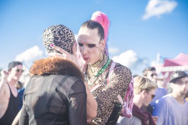 Amsterdam, Hollanda - 30 Temmuz 2017: Westerpark Milkshake Festivali'nde bir arkadaşının kulağına fısıldayan leopar desenli kıyafetli travesti giyinmiş