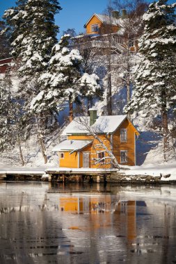Sweedish landscape with wooden cabin near frozen water near Stockholm, Sweden clipart