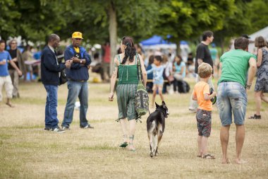 Amsterdam, Hollanda - 5 Temmuz 2015: Amsterdam Roots Open Air,Park Frankendael'de düzenlenen kültür festivali sırasında ziyaretçiler, bir köpekle yürüyen woamn