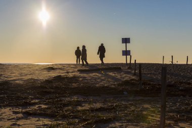 Romantik kış gün batımı, L'aiguillon sur Mer, Vendee, Fransa tarafından sahilde yürüyen insanların silueti