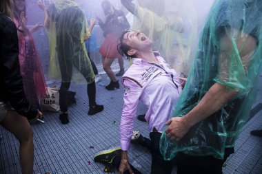 Amsterdam, Hollanda - 29 Temmuz 2017: Westerpark'taki Milkshake Festivali'nde yağmur ponçolarıyla yağmur altında dans eden insanlar