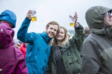 Traena, Norveç - 6 Temmuz 2017: Küçük Traena adasında düzenlenen müzik festivali Traenafestival'de kadehlerini tutan ve tezahürat taå Ä±an genÃ§ Ã§ift