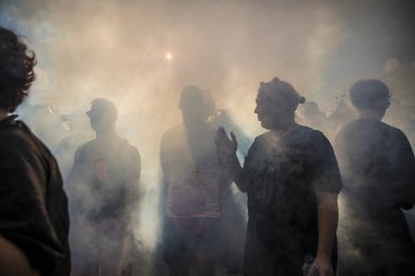 Amsterdam, Hollanda - 30 Temmuz 2017: Westerpark'taki Milkshake Festivali'nde güneşin parıldayarak duman içinde dans eden insanların silueti