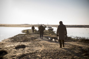 Doğal rezerv Casse de la Belle Henriette, l'Aiguillon sur Mer, Vendee, Fransa lagün tarafından gün batımında yürüyen insanların arkadan aydınlatmalı siluetler