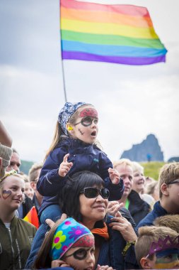 Traena, Norveç - 7 Temmuz 2017: Annesinin omzundaki küçük kız, Norveçli eşcinsel korosu Oslo Fagittkor'un Traenafestival'deki konserini izledi, traena adasında düzenlenen müzik festivali