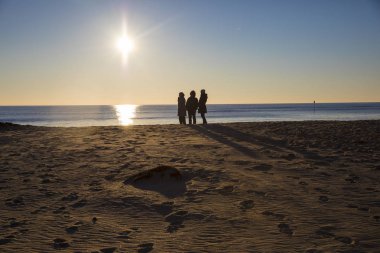 Romantik kış gün batımı, L'aiguillon sur Mer, Vendee, Fransa tarafından sahilde yürüyen insanların silueti