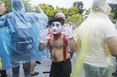 Amsterdam, Hollanda - 29 Temmuz 2017: Westerpark'taki Milkshake Festivali'nde yağmur ponçolarıyla yağmur altında dans eden insanlar. Bir adam pandomim Marceau gibi giyinmiş.