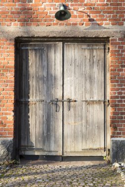 Kırmızı tuğla duvar ve eski lambalı ahşap kapı.
