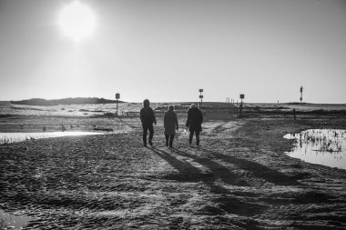 Doğal rezerv Casse de la Belle Henriette, l'Aiguillon sur Mer, Vendee, Fransa lagün tarafından gün batımında yürüyen insanların arkadan aydınlatmalı siluetler