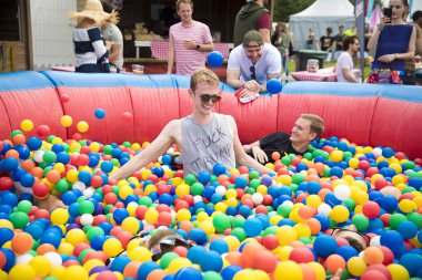 Amsterdam, Hollanda - 29 Temmuz 2017: Westerpark'taki Milkshake Festivali'nde renkli bir top havuzunda eğlenen gençler havada top atıyor. Bir adamın tişörtü var. 