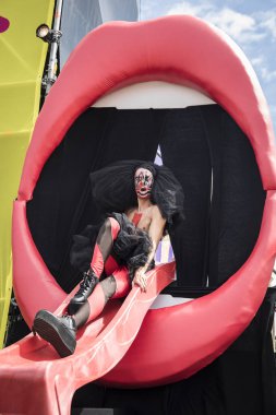 Amsterdam, Hollanda - 29 Temmuz 2017: Westerpark'taki Milkshake Festivali'nde kırmızı dudaklı büyük bir ağızdan dans eden travesti, yüzünde Fake yazılı bir gösteri