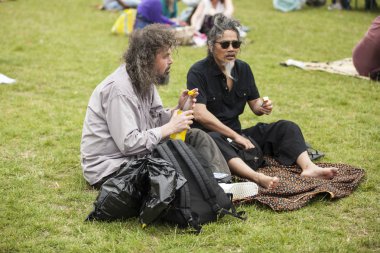 Amsterdam, Hollanda - 5 Temmuz 2015: Amsterdam Roots Open Air'de çimlerin üzerinde oturan 2 arkadaş, Park Frankendael'de 05/07/2015 tarihinde düzenlenen kültür festivali