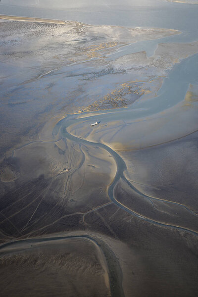aerial view of the mudflat coastline at low tide with water winding in the mud and sand bank, Frisian island Ameland, The Netherlands