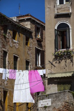 Çamaşırları kurumaya bırakılmış tipik bir Venedik evi cephesi. İşarette, en yakın Vaporetto teknesine ulaşmak için