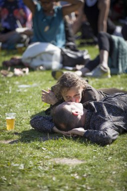 Amsterdam, Hollanda - 3 Temmuz 2016: Roots Open Air festivali sırasında çimlerin üzerinde yatan erkek ve kadın çift öpüşüyor