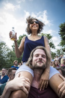 Amsterdam, Hollanda - 23 Temmuz 2016: 2016 Gay Euro Pride için Vondelpark'ta pembe cumartesi kutlamaları sırasında beyaz erkek arkadaşının omzunda oturan genç siyahi kadın