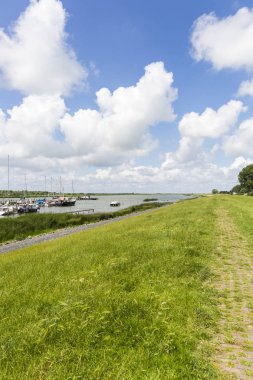 Beyaz bulutlar ile mavi gökyüzü ile Friesland çim dike