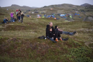 Traena, Norveç - 11 Temmuz 2014: Traenafestival'de, küçük Traena adasında düzenlenen müzik festivalinde, tepenin tepesinde gece yarısı güneşinin manzarasına hayran olan insanlar